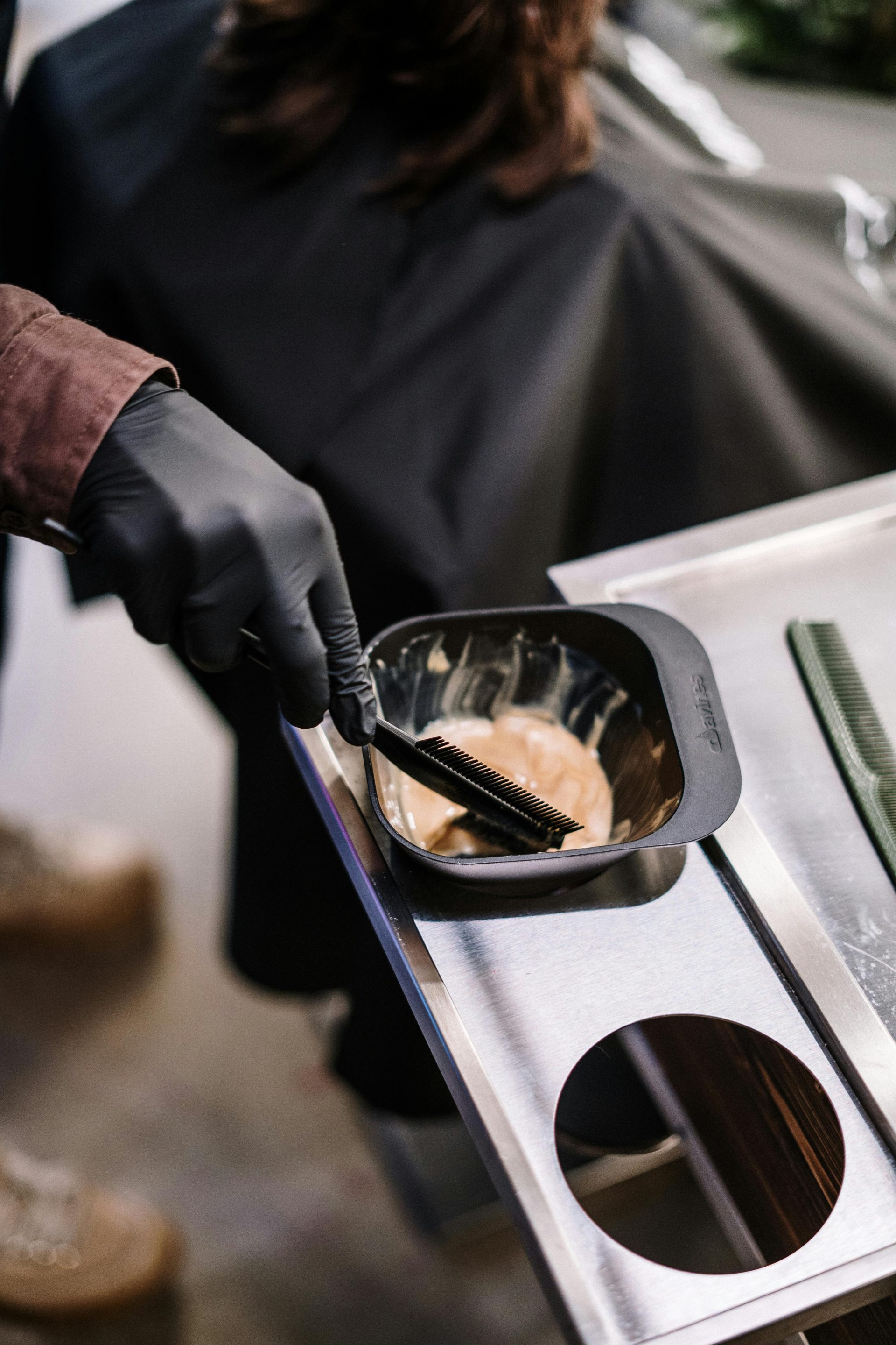Stylist preparing hair dye at a salon with professional tools ready for application.